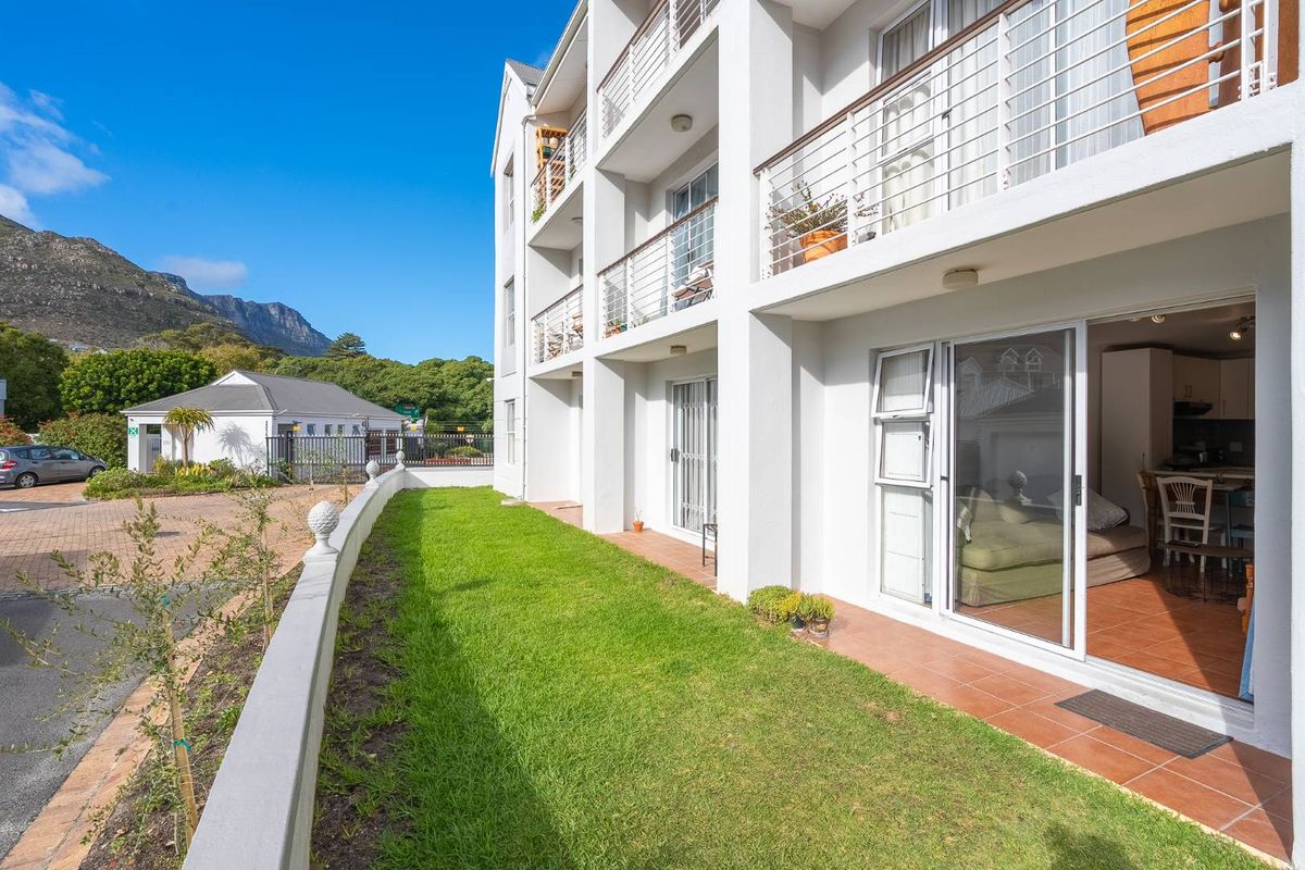 Ground floor apartment featuring a private tiled patio, small lawn area, and direct access to the living space through sliding glass doors.