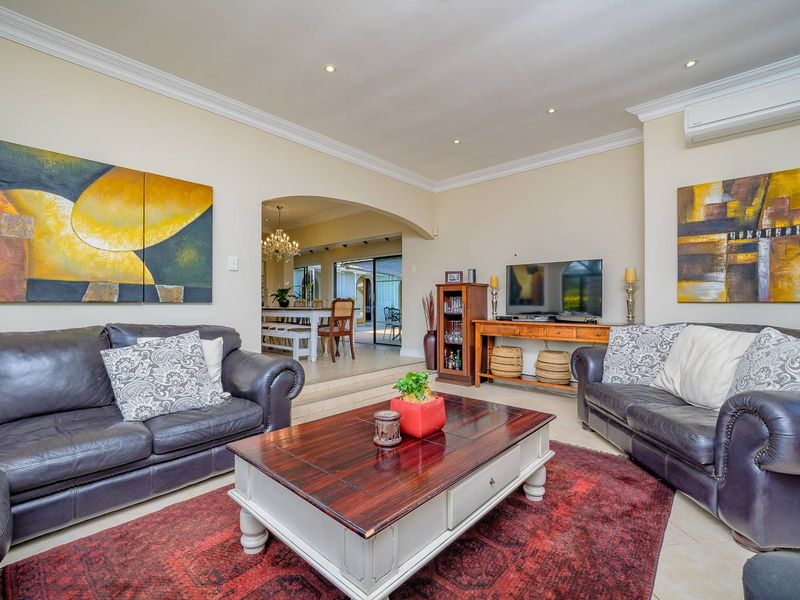 A spacious living room featuring tiled flooring, crown molding, recessed lighting, and a split-system air conditioner, with an open-plan flow to the dining area.