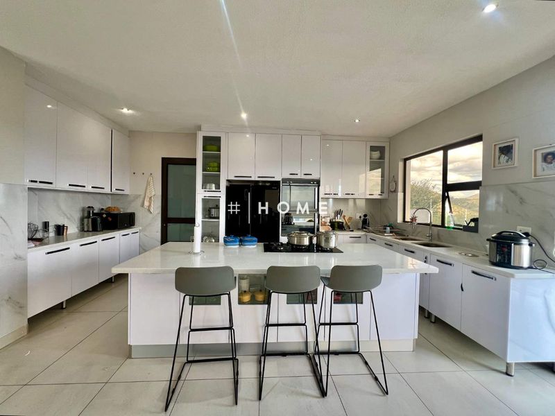 Modern kitchen featuring high-gloss white cabinetry, a central island with a gas hob, quartz countertops, and large format floor tiles.