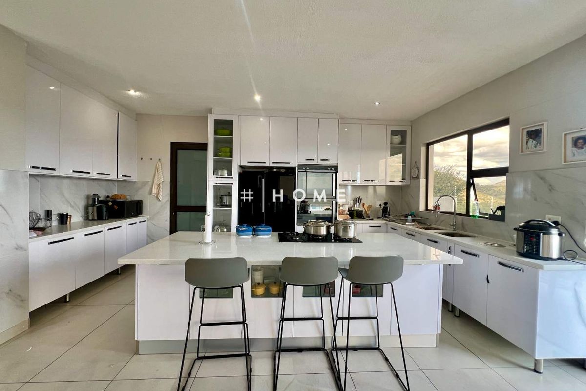 Modern kitchen featuring high-gloss white cabinetry, a central island with a gas hob, quartz countertops, and large format floor tiles.