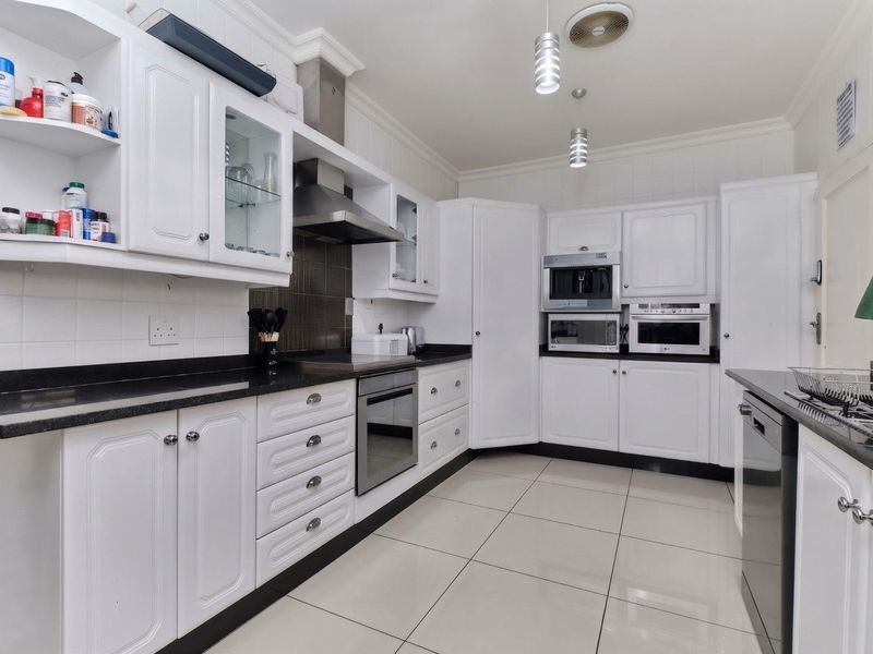 A well-maintained kitchen featuring white cabinetry, granite countertops, built-in appliances, and tiled flooring, offering a clean and functional workspace.
