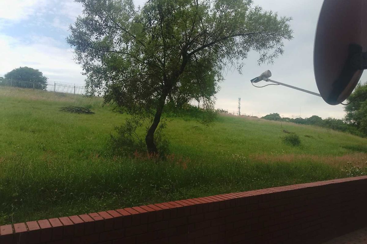 A view of the rear garden area featuring a brick boundary wall and a satellite dish mounted on the exterior.
