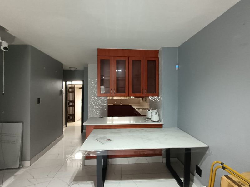 A compact kitchen area featuring wooden cabinetry, stone countertops, and tiled flooring, providing a functional space for meal preparation.