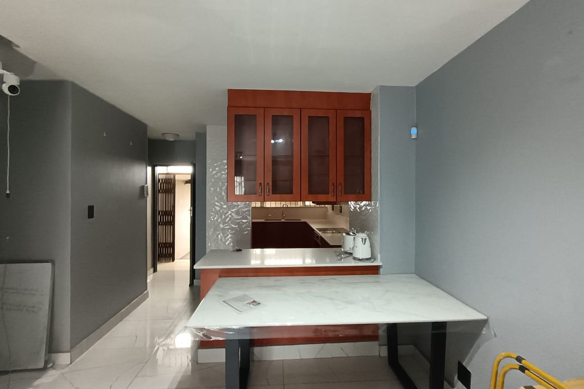 A compact kitchen area featuring wooden cabinetry, stone countertops, and tiled flooring, providing a functional space for meal preparation.