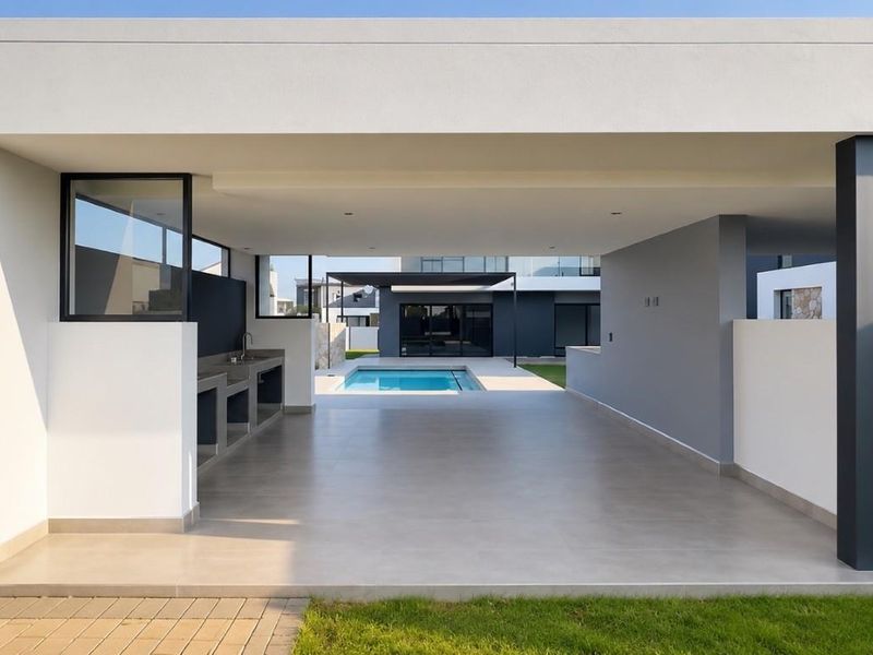 Modern covered patio featuring a built-in braai and outdoor sink, overlooking a private swimming pool in a contemporary architectural setting.
