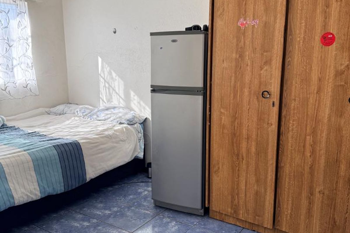 A bedroom featuring built-in wooden cupboards and tiled flooring, providing functional storage space.