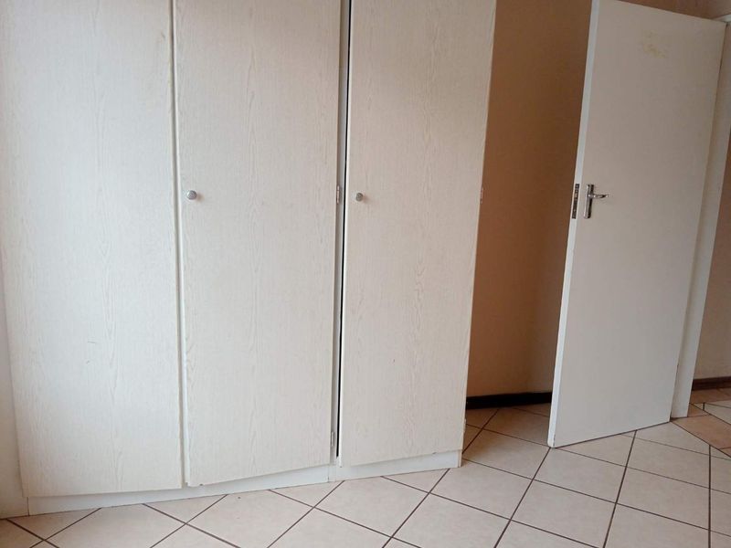 A bedroom featuring built-in cupboards and tiled flooring, presented as an empty space ready for personalization.