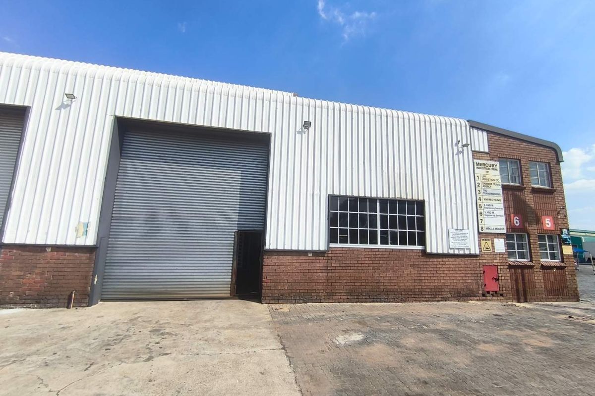 Front elevation of an industrial warehouse unit featuring a large roller shutter door, brick and metal cladding, and paved exterior access area.