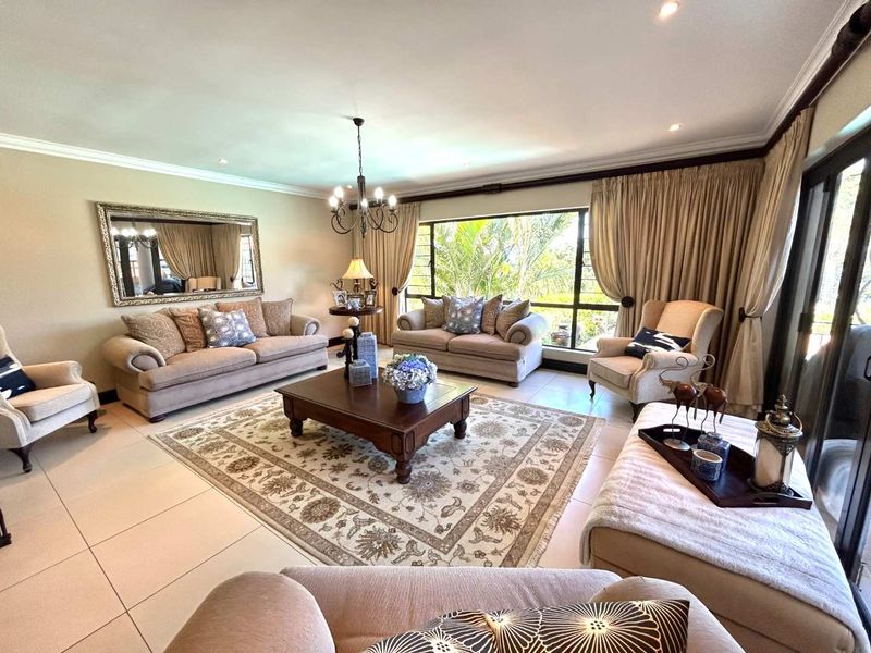 A spacious and well-lit living room featuring large windows, tiled flooring, and elegant crown molding, offering a comfortable and inviting atmosphere.