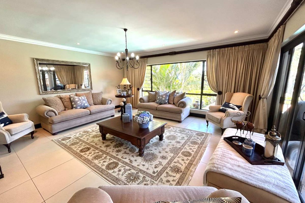 A spacious and well-lit living room featuring large windows, tiled flooring, and elegant crown molding, offering a comfortable and inviting atmosphere.