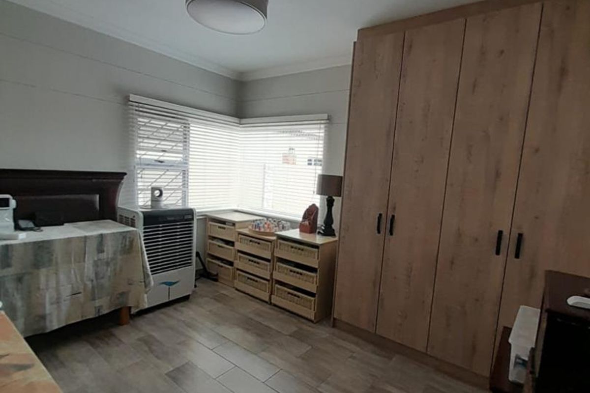 A well-maintained bedroom featuring wood-look tile flooring, built-in wooden cabinetry, and a ceiling fan.