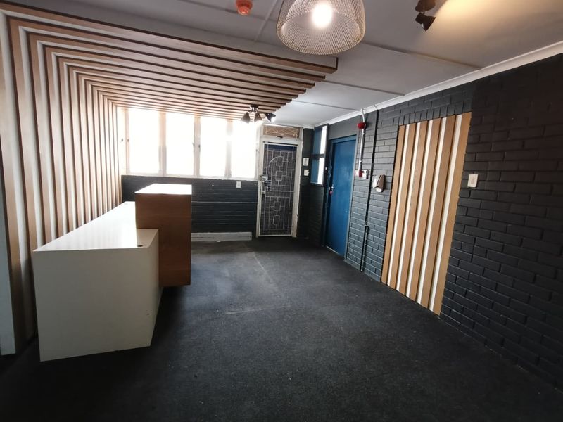 Modern industrial-style entry area featuring timber slat wall accents, painted brickwork, and a built-in reception counter, providing a professional and welcoming space.