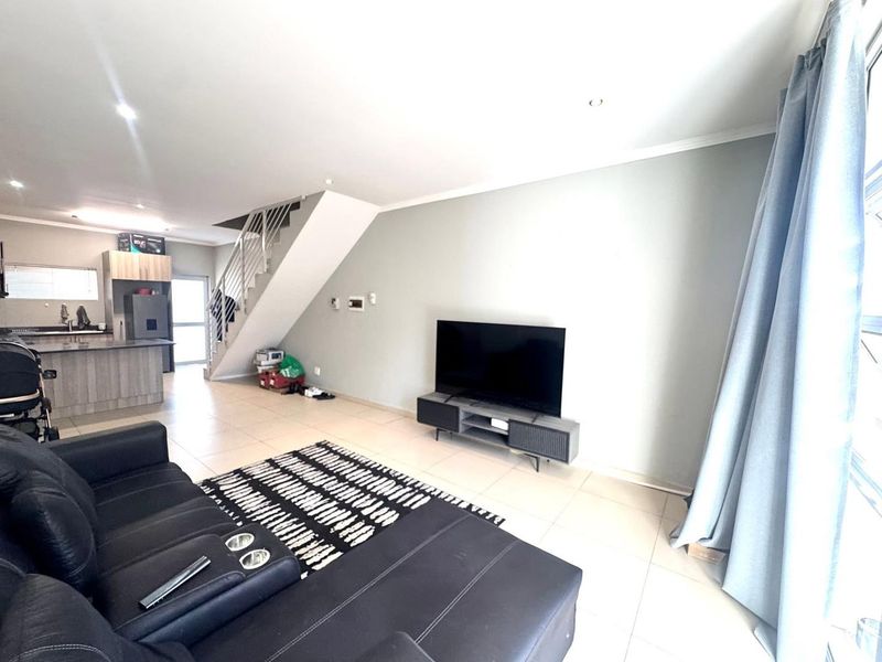 Open plan living area featuring tiled floors, a modern kitchen with island, and a staircase leading to the upper level.