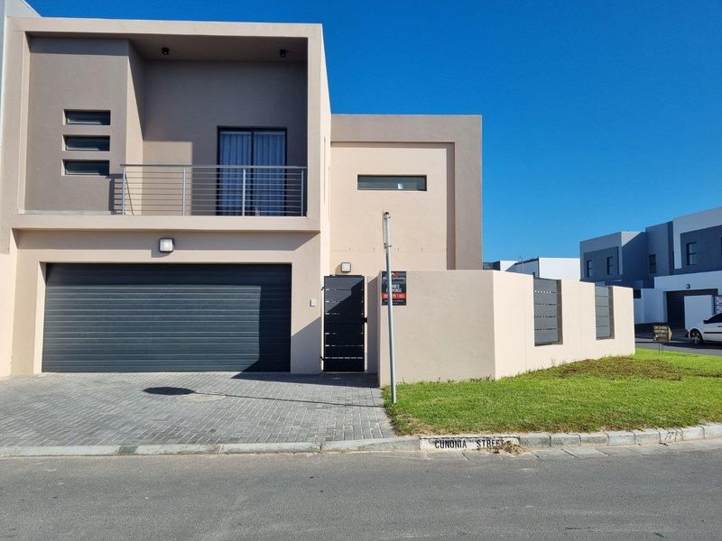 Modern double-storey residential facade featuring a paved driveway, integrated double garage, and a private balcony with metal railing.