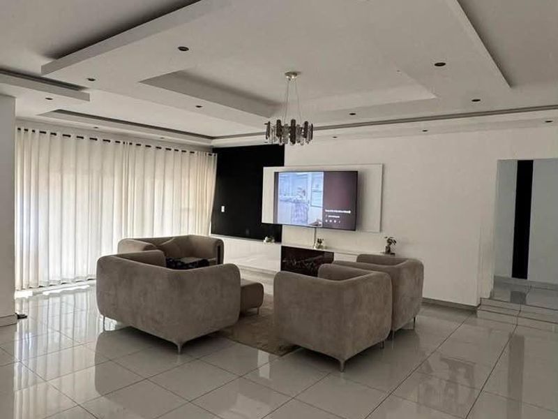 Modern living room featuring high-gloss tiled flooring, a sophisticated recessed ceiling with integrated lighting, and a sleek built-in media wall.