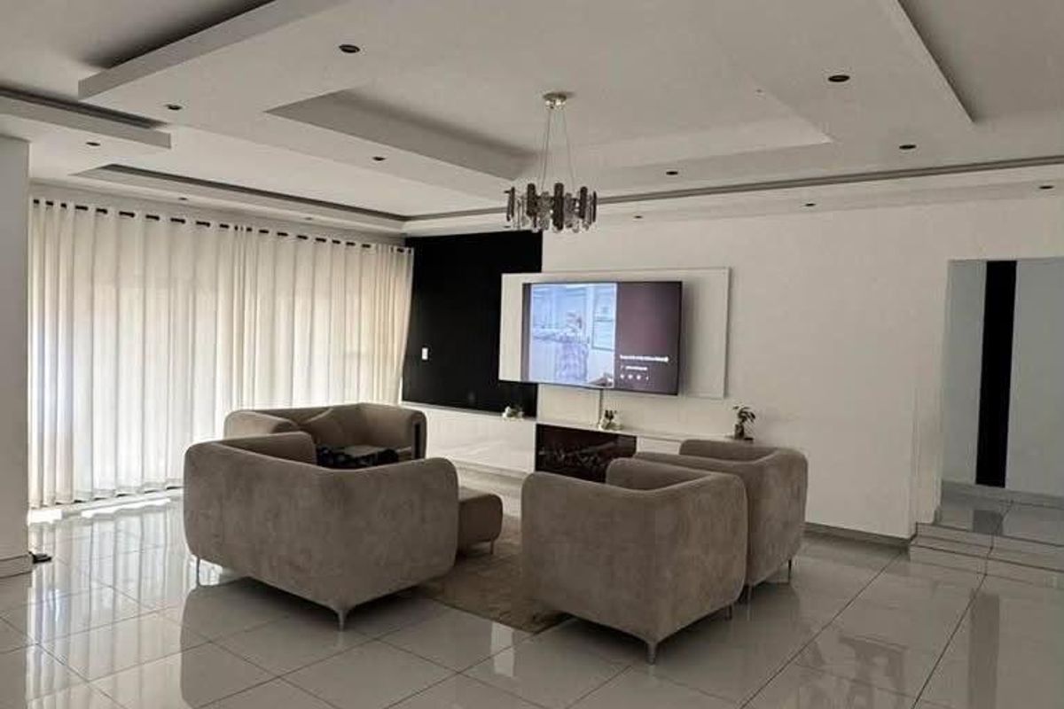 Modern living room featuring high-gloss tiled flooring, a sophisticated recessed ceiling with integrated lighting, and a sleek built-in media wall.