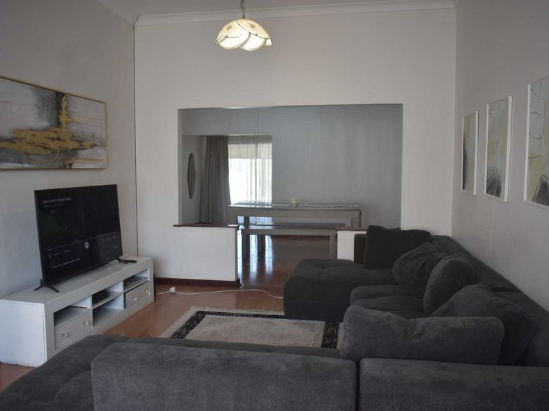 A living room featuring laminate flooring and a pass-through opening connecting to the adjacent dining area.