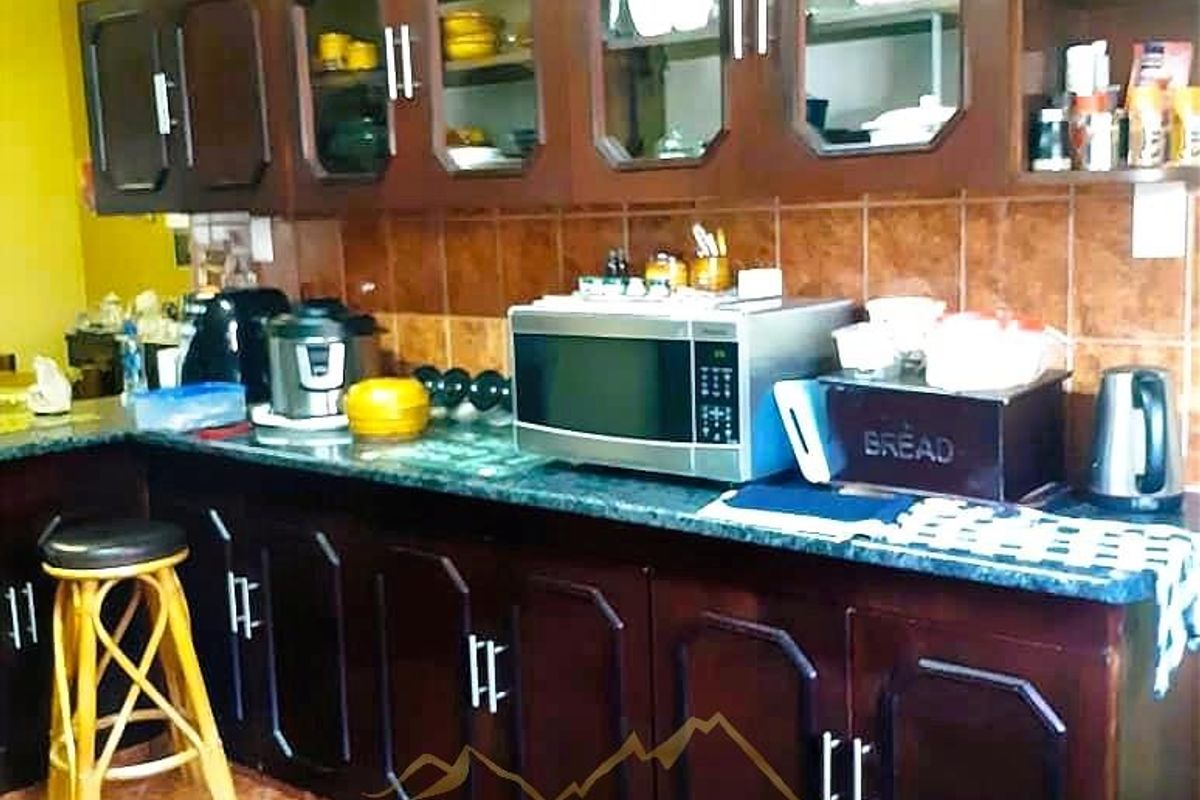 A functional kitchen featuring dark wood cabinetry, tiled backsplash, and durable countertops, providing ample storage and workspace for daily meal preparation.