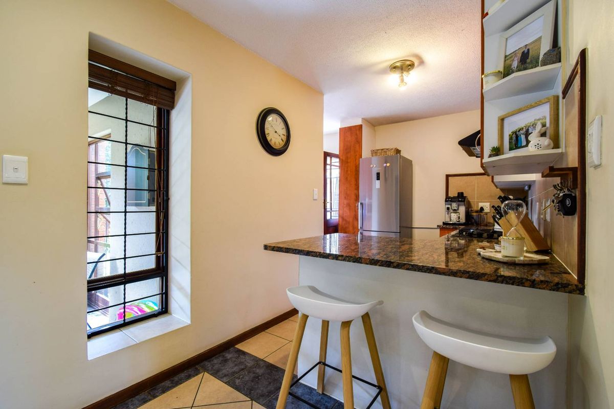 A functional kitchen featuring a granite breakfast bar, tiled flooring, and built-in shelving, providing a practical space for meal preparation and casual dining.