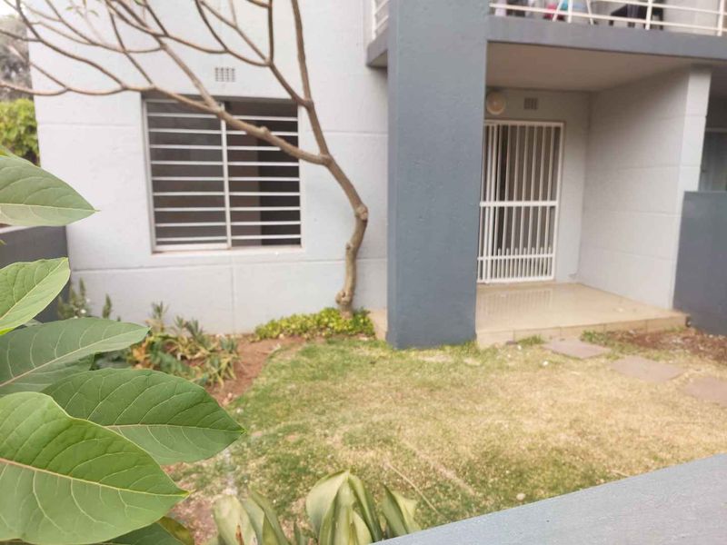 Ground floor apartment exterior featuring a small private garden, tiled patio area, and secure sliding door access.