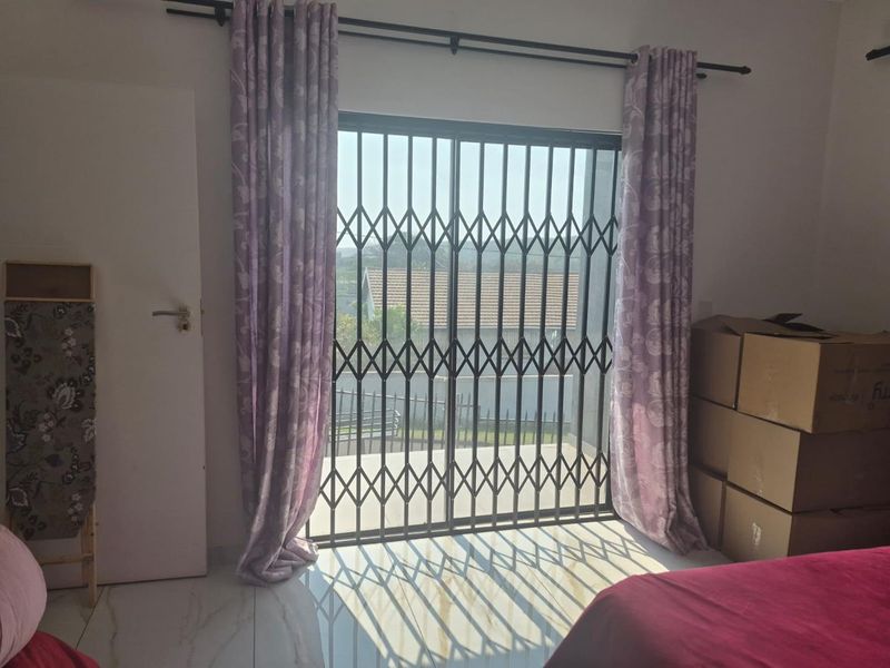 A bedroom featuring tiled flooring and a sliding glass door with a security gate, providing access to an outdoor area.