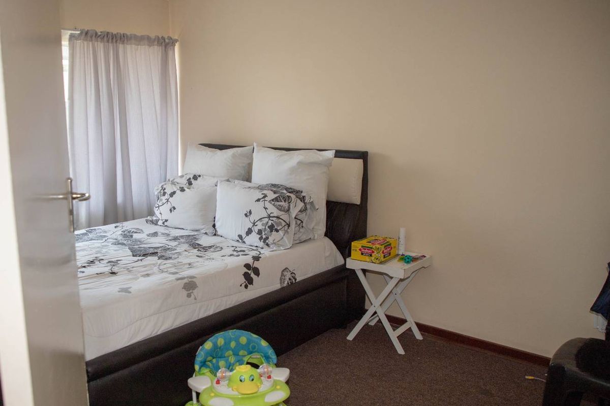 A standard bedroom featuring carpeted flooring and a window with curtain tracks.