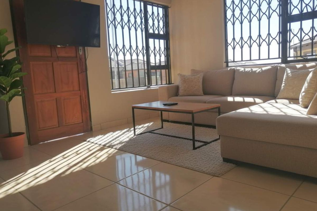 A bright living room featuring large windows with security bars, tiled flooring, and a solid wood door.
