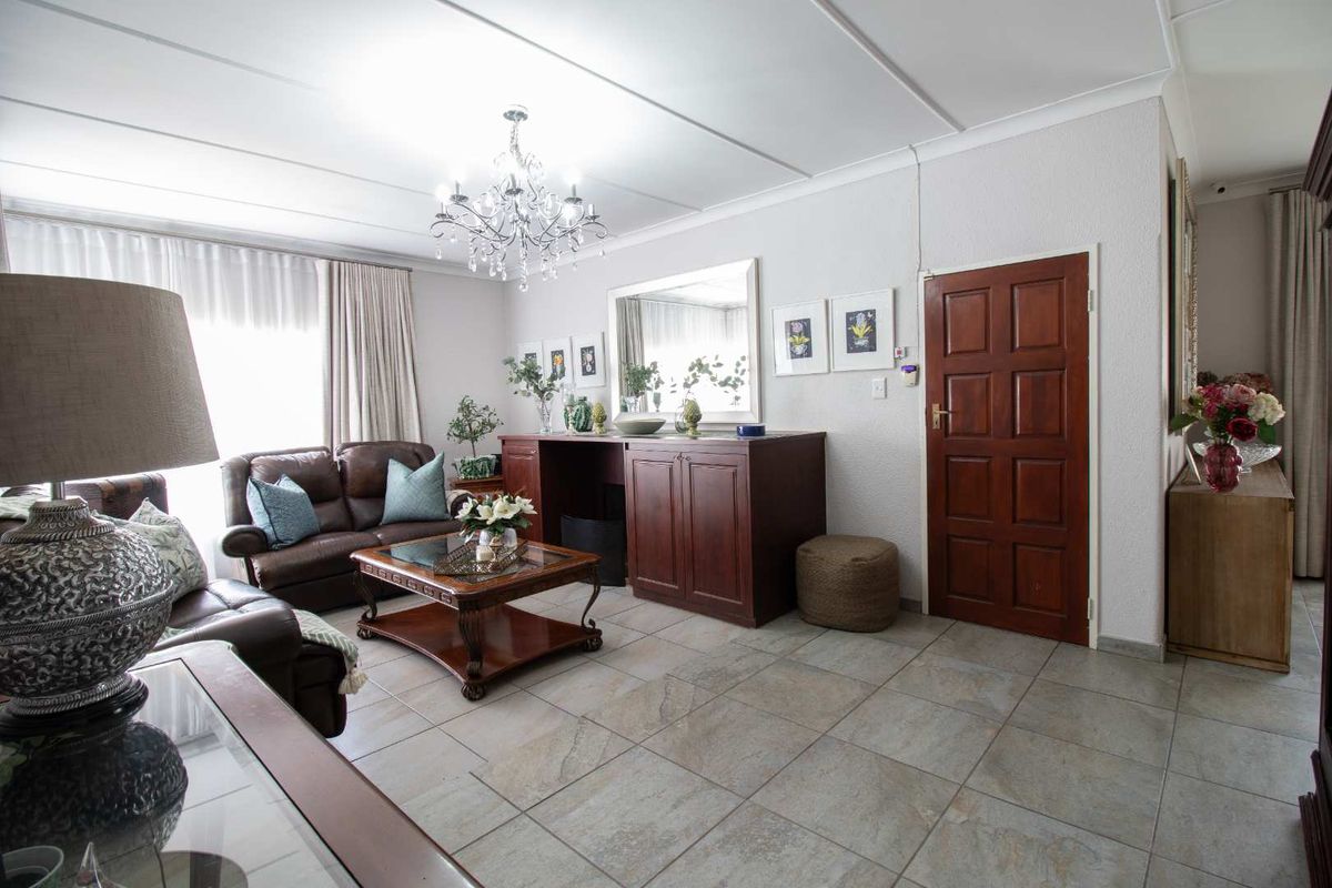 A well-maintained living room featuring neutral tiled flooring, a decorative crystal chandelier, and built-in wooden cabinetry, offering a classic and comfortable living space.
