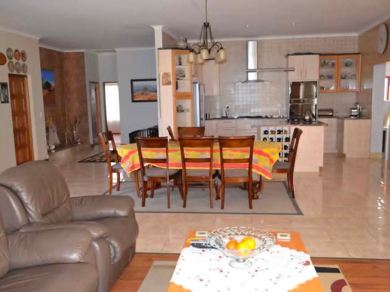 Open plan living and dining area featuring a functional kitchen with built-in cabinetry, integrated appliances, and tiled flooring throughout.