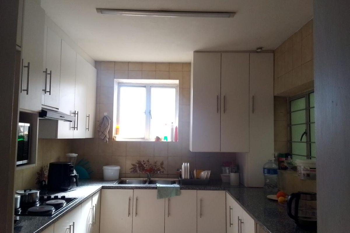 A functional kitchen featuring white built-in cabinetry, laminate countertops, a double bowl sink, and a built-in hob with an extractor fan.