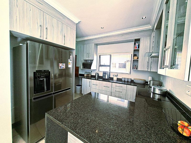Modern kitchen featuring granite countertops, extensive built-in cabinetry, and recessed lighting, offering a functional and well-maintained workspace.