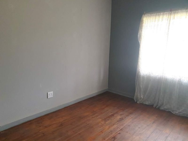 An empty bedroom featuring original timber flooring and a neutral color scheme, ready for personalization.