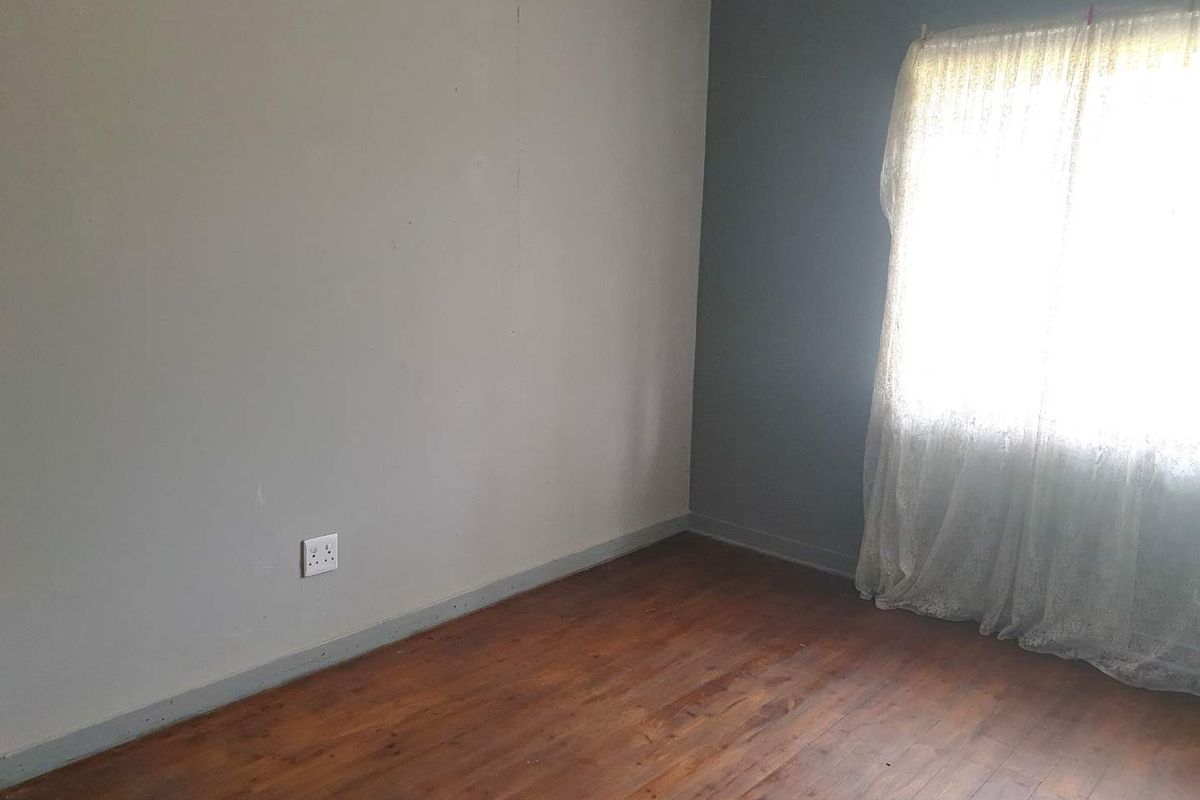 An empty bedroom featuring original timber flooring and a neutral color scheme, ready for personalization.