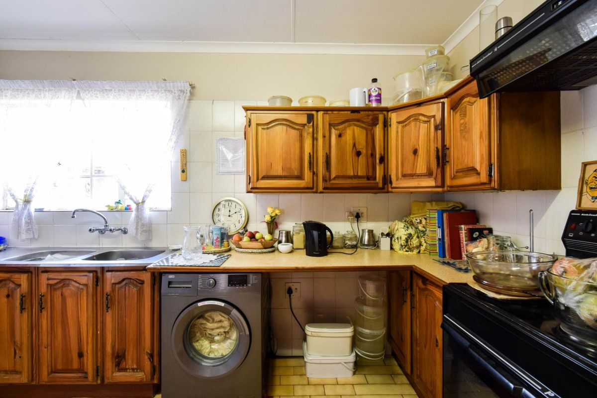 A functional kitchen featuring timber cabinetry, a double sink, integrated laundry space, and a built-in oven with an extractor fan.