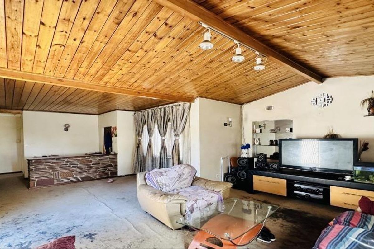 Spacious living room featuring a distinctive timber-clad ceiling, track lighting, and a built-in stone-clad bar counter.