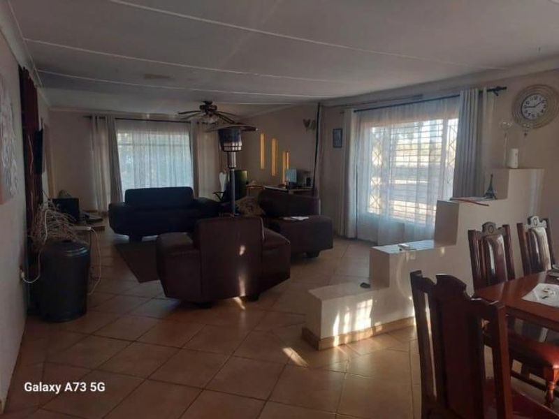 Spacious open-plan living and dining area featuring tiled flooring, a ceiling fan, and a decorative partition wall.