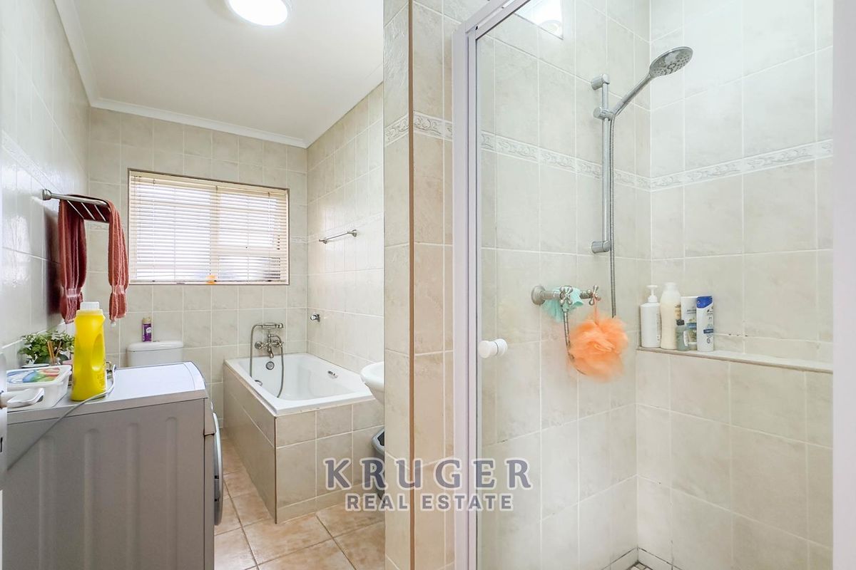 A functional bathroom featuring a built-in bathtub, separate shower enclosure, toilet, and washbasin with neutral wall and floor tiling.