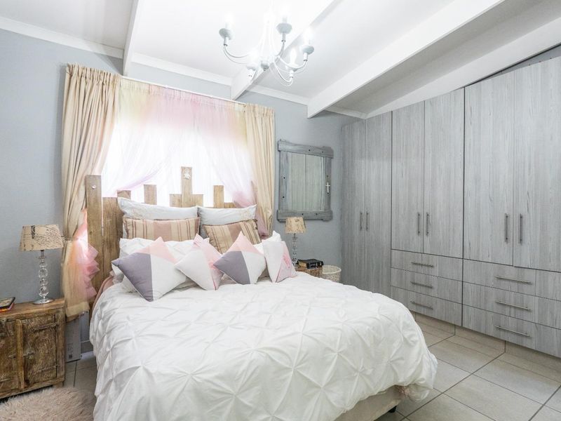 A well-maintained bedroom featuring built-in cupboards, tiled flooring, and exposed ceiling beams, providing a clean and functional living space.