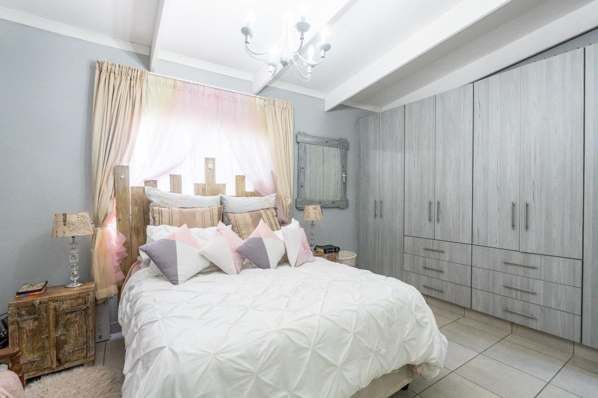 A well-maintained bedroom featuring built-in cupboards, tiled flooring, and exposed ceiling beams, providing a clean and functional living space.