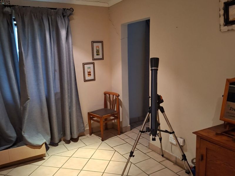 Bedroom featuring tiled flooring and a ceiling fan, showing a visible structural crack on the wall near the doorway.