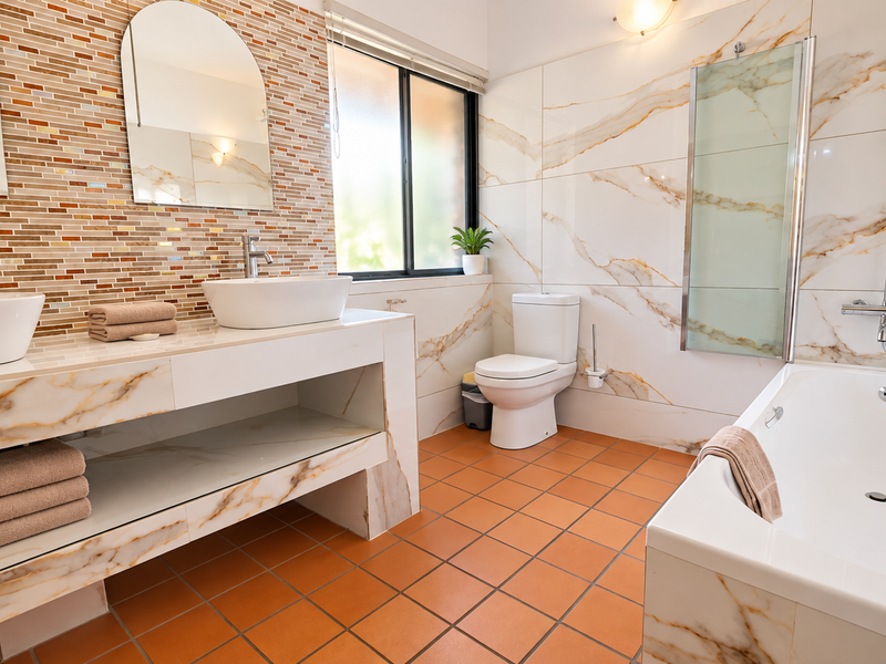 Modern bathroom featuring a double vanity with vessel sinks, marble-look wall tiles, a built-in bathtub with shower attachment, and terracotta-style floor tiles.
