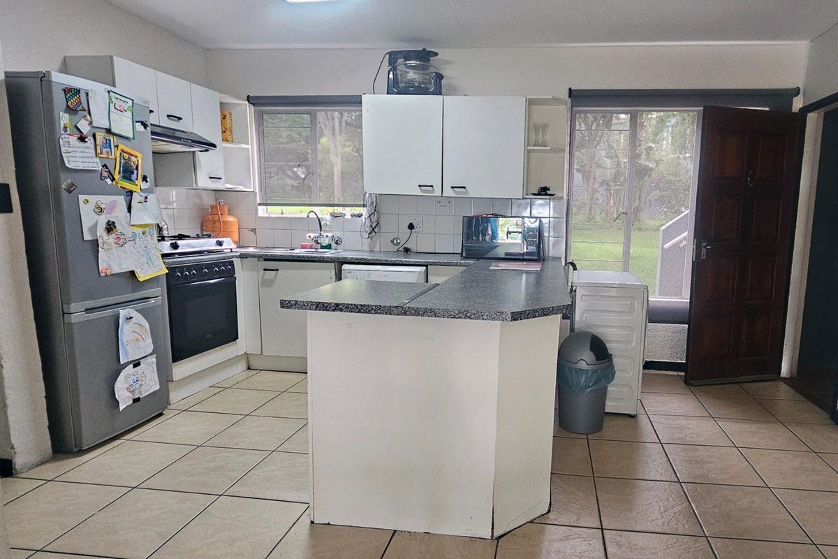 Functional kitchen featuring white cabinetry, laminate countertops, tiled flooring, and direct access to the exterior through a glass-paneled door.