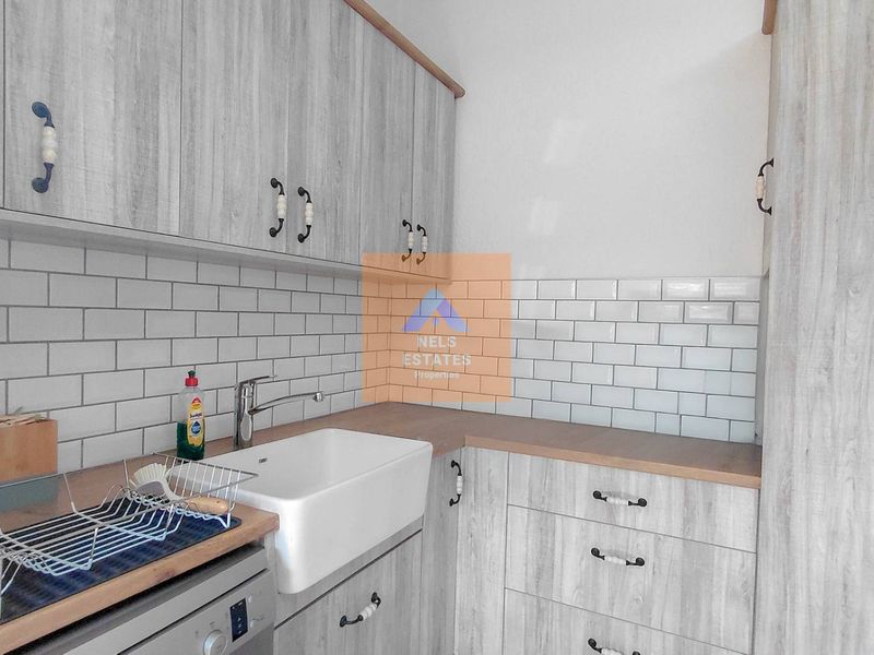 A functional scullery featuring a farmhouse sink, subway tile backsplash, and modern wood-grain cabinetry with ample storage space.