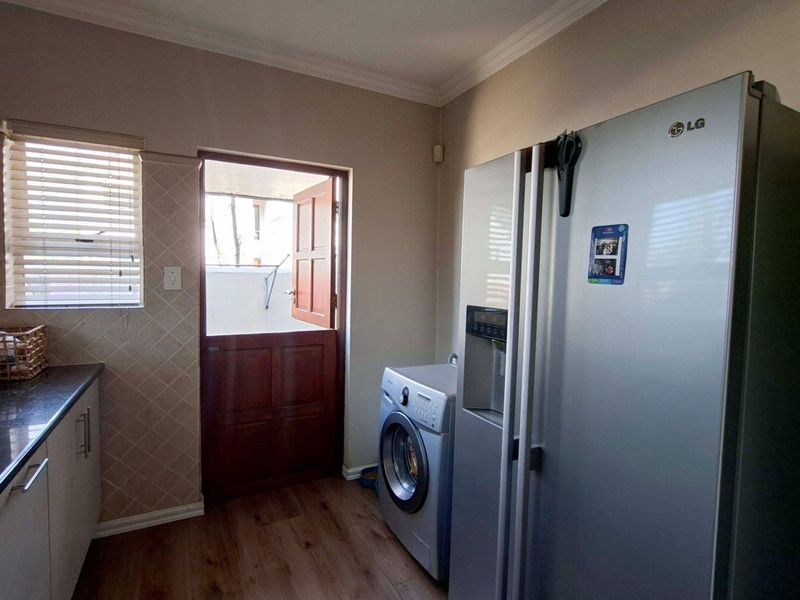 A functional scullery area featuring built-in cabinetry, granite countertops, a sink, and a stable door providing direct access to the exterior.