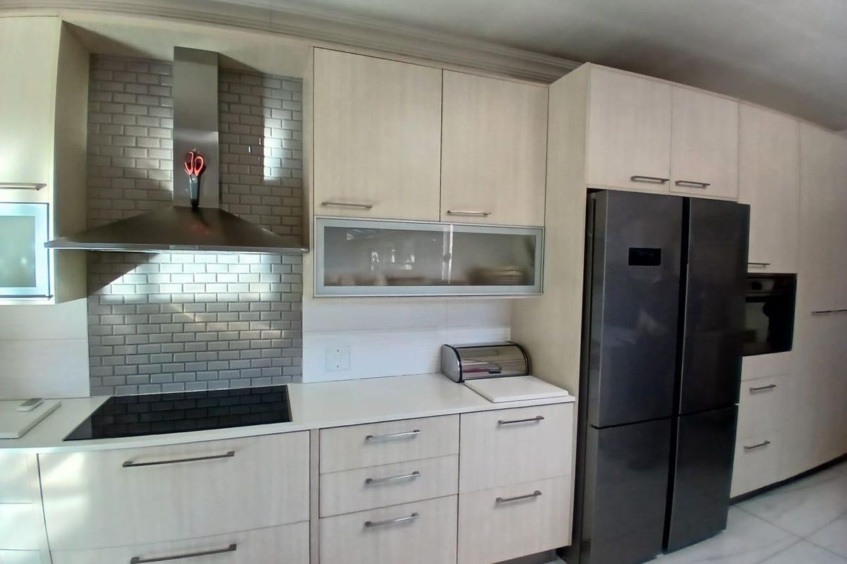 Modern kitchen featuring light wood cabinetry, subway tile backsplash, stainless steel extractor fan, induction hob, and integrated appliances.