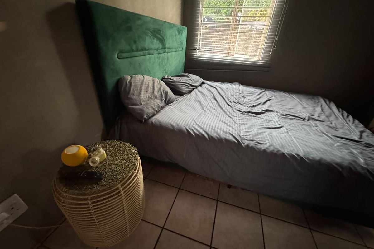 A bedroom featuring tiled flooring and venetian blinds, providing a functional space with neutral wall tones.