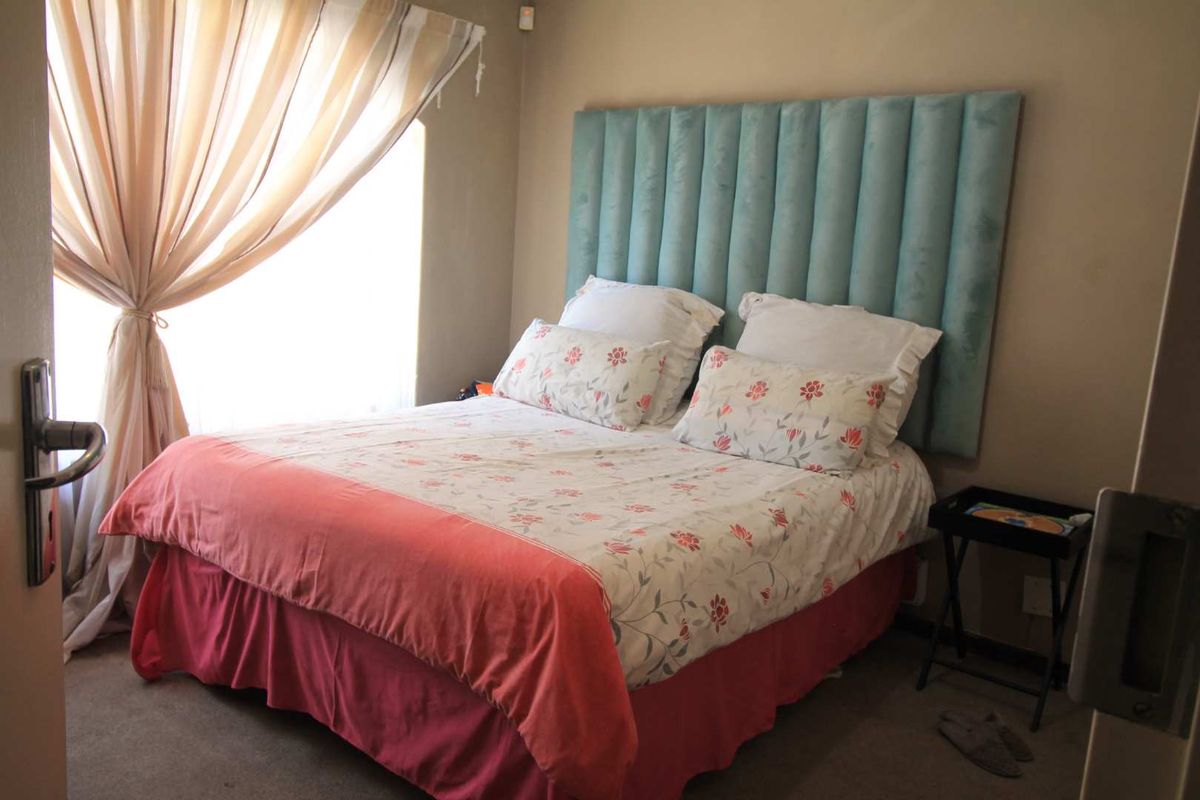 A cozy bedroom featuring a built-in headboard and carpeted flooring, providing a comfortable and functional sleeping space.