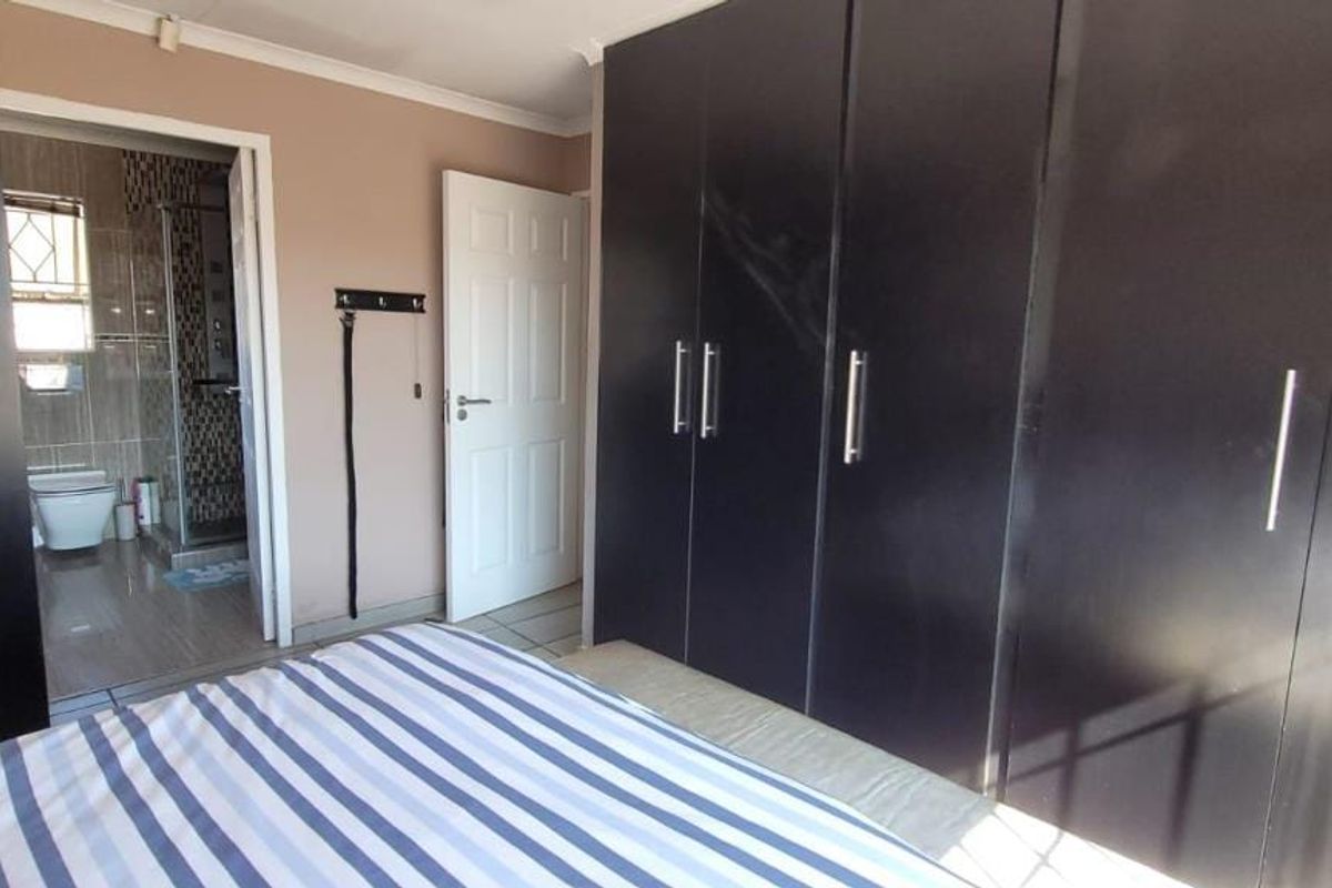 Bedroom featuring dark built-in cupboards and direct access to an en-suite bathroom with tiled finishes.