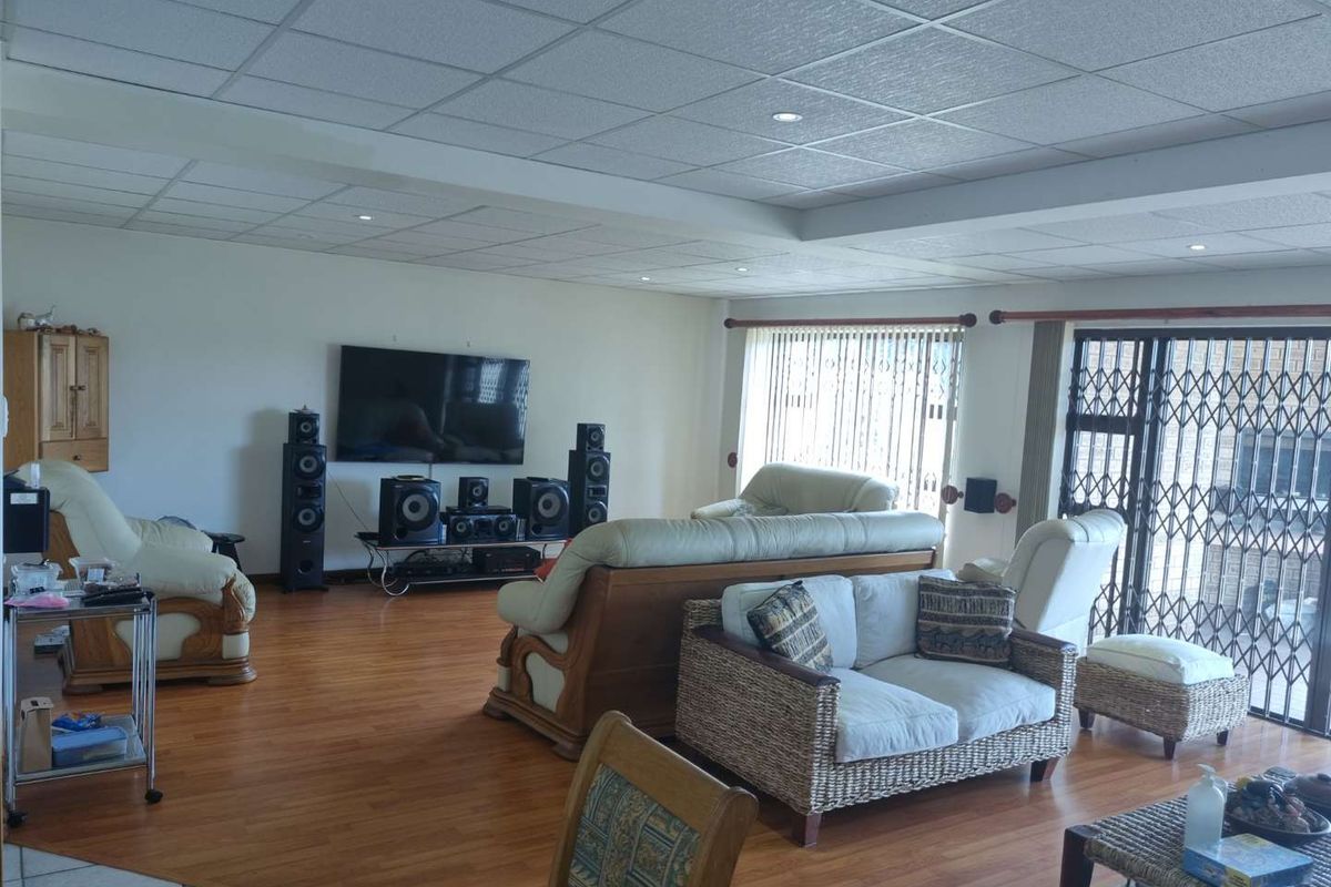 Spacious living area featuring wood-look laminate flooring, recessed lighting, and a drop ceiling, with direct access to an outdoor patio through sliding doors.