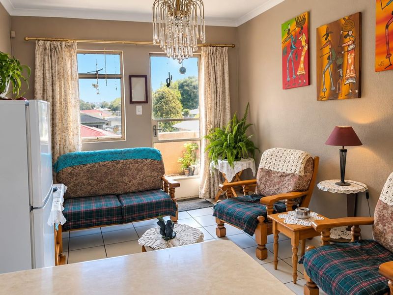 Open plan living area featuring tiled flooring, a decorative crystal chandelier, and direct access to a balcony through a sliding glass door.